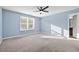 A bright bedroom with large windows, neutral carpet, a ceiling fan, and light blue walls at 2056 Wildflower Way, Conyers, GA 30012