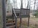 Image displays a back deck with weathered wood and railing, set among trees with a view of a distant house at 3321 Border Dr, Stone Mountain, GA 30087
