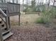 Backyard view from the deck stairs, showing leaves covering the ground and glimpses of the surrounding wooded area at 3321 Border Dr, Stone Mountain, GA 30087