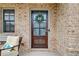 Close-up of a stylish front door adorned with a wreath, set against a backdrop of brick and a cozy porch at 3000 Smyrna Grove Dr, Smyrna, GA 30082