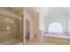 Bright bathroom with a large glass shower and a soaking tub under an arched window at 3184 Islesworth Trce, Duluth, GA 30097