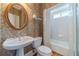 Bathroom features patterned wallpaper, pedestal sink and framed mirror above toilet and tub/shower combo at 3184 Islesworth Trce, Duluth, GA 30097