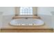 Close-up of a soaking tub with tile surround and an arched window at 3184 Islesworth Trce, Duluth, GA 30097