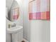 Elegant powder room featuring a pedestal sink, round mirror and stylish artwork at 5756 Tillman Way, Powder Springs, GA 30127