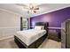 Bright bedroom featuring gray carpet, purple accent wall, ceiling fan, and natural light from the window at 1770 Rockland Se Dr, Atlanta, GA 30316