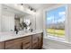 Bright bathroom with a double vanity, sleek faucets, and a large window offering scenic views at 5270 Birch Valley Rd, Cumming, GA 30028