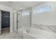 Elegant bathroom with marble tile, soaking tub, and glass shower enclosure at 5270 Birch Valley Rd, Cumming, GA 30028