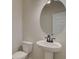 Elegant powder room featuring a pedestal sink, round mirror, and a modern faucet at 4361 Portsbrook Ave, Snellville, GA 30039