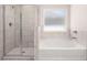 Bathroom featuring a tub and separate shower with white marbled wall tiles and a window at 13520 Whitman Lane, Covington, GA 30014