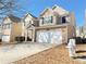 Two-story house with a stone and beige facade, two-car garage, and a neat front yard at 585 Briarhurst Ct, Lawrenceville, GA 30046