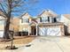 Two-story house with stone and beige exterior, a two-car garage, and a landscaped yard at 585 Briarhurst Ct, Lawrenceville, GA 30046