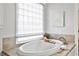 Bright bathroom with soaking tub, window with blinds, and beige tiled countertop at 6355 Indian Acres Trl, Tucker, GA 30084