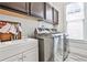 Bright laundry room with modern washer and dryer, a sink and wooden cabinets above at 1250 Atherton Park, Roswell, GA 30076