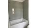 Bright bathroom showcasing a white bathtub and shower combination with light gray tiled walls at 5043 Baywood Ln, Woodstock, GA 30188