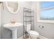Bathroom featuring pedestal sink, oval mirror, storage unit, and a window with a view at 692 Rose Palm Ln, Atlanta, GA 30315