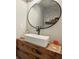 Modern bathroom features a wood vanity with a vessel sink and a round mirror at 327 Balaban Cir, Woodstock, GA 30188