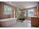 Elegant bathroom with a soaking tub, marble tile, glass enclosed shower with gold hardware, and a window at 4395 Woodland Brook Se Dr, Atlanta, GA 30339