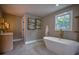 Modern bathroom features a soaking tub with gold fixtures, neutral paint colors, and decor at 4395 Woodland Brook Se Dr, Atlanta, GA 30339