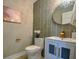 Stylish powder room with grey tiled walls, vessel sink, elegant vanity, and decorative mirror and lighting at 4395 Woodland Brook Se Dr, Atlanta, GA 30339