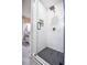 Modern walk-in shower with sleek glass door, white tiled walls, and black hexagon-tiled floor at 4395 Woodland Brook Se Dr, Atlanta, GA 30339