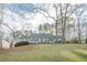Front view of a charming light blue house nestled amongst mature trees at 118 Knotts Landing Dr, Woodstock, GA 30188