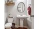 Elegant powder room with pedestal sink, oval mirror, and hardwood floors at 4200 Oxcliffe Grv, Suwanee, GA 30024