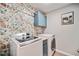 Laundry room with floral wallpaper, blue cabinets, and a washer and dryer at 6285 Vista Crossing Way, Cumming, GA 30028