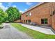 View of a large brick home with a patio and gravel driveway in a lush, green setting at 3505 Watson Rd, Cumming, GA 30028