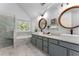 Bright bathroom featuring a glass enclosed shower, a soaking tub, and a dual sink vanity with gray cabinets at 889 City Park Se Dr, Atlanta, GA 30312