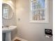 Bathroom with pedestal sink, round mirror and view to the outside at 40 Brompton Dr, Dallas, GA 30157