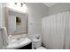Bright bathroom features a vanity with a decorative framed mirror and a shower with a white curtain at 2116 Tidal Cv, Lawrenceville, GA 30043