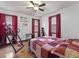 Bedroom featuring a patterned quilt, hardwood floors, exercise equipment, and windows with red curtains at 5295 Ridge Rd, Douglasville, GA 30134