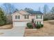 Split-level home with light siding, black shutters, a garage, and landscaped bushes near the front entrance at 100 Arthurs Ln, Covington, GA 30016