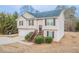 Split-level home with light siding, black shutters, a garage, landscaped bushes, and a front entrance staircase at 100 Arthurs Ln, Covington, GA 30016