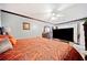 Main bedroom with large TV and orange patterned bedding at 1956 Spencer Oaks Ln, Lithonia, GA 30058