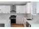 Modern kitchen with white cabinets, marble countertops, and a stainless steel range hood at 2195 Springdale Sw Rd, Atlanta, GA 30315