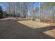 Large flat backyard featuring dormant grass and a border of natural landscaping with mature trees in the distance at 4760 Green Summers Dr, Cumming, GA 30028