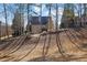 View of the backyard of a tan two story home with a deck and steps, surrounded by bare trees and lawn at 4760 Green Summers Dr, Cumming, GA 30028