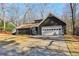 Ranch style home with dark siding, white garage door, and landscaping at 645 Trailmore Pl, Roswell, GA 30076