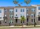 Three-story townhouses with brick and white siding, landscaping, and street view at 2505 Astaire Nw Ct, Atlanta, GA 30318