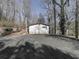Rear view of the home with a gravel driveway and wooded area at 337 Theodore Cox Cir, Canton, GA 30114