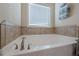 Relaxing bathroom with soaking tub, tile surround, and natural light at 9994 Inisfree Dr, Johns Creek, GA 30022