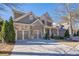 Two-story home with stone and siding accents, three-car garage, and front porch at 9994 Inisfree Dr, Johns Creek, GA 30022