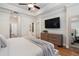 Comfortable main bedroom featuring a tray ceiling, ceiling fan, dresser, and large television at 124 Everley Walk, Alpharetta, GA 30009