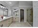 Bathroom featuring double vanities, walk-in shower, large mirror, and neutral colored tile flooring at 5915 Masters Club Dr, Suwanee, GA 30024