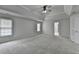 Spacious bedroom featuring neutral walls, plush carpeting, tray ceiling with fan, and natural light from two windows at 5915 Masters Club Dr, Suwanee, GA 30024