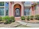 Close-up of the brick archway, front door with a wreath, and stone walkway with landscaped bushes at 5915 Masters Club Dr, Suwanee, GA 30024