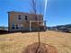 Back exterior view of new construction home showcasing the yard with a covered patio and a clear blue sky at 405 Westmarch Cir, Loganville, GA 30052