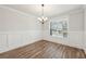 Bright dining room with traditional wainscoting, wood floors, and a modern light fixture at 407 Westmarch Cir, Loganville, GA 30052