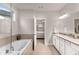 Bright bathroom featuring a soaking tub, double sink vanity, and a doorway to the bedroom at 505 Flyingbolt Run, Canton, GA 30115